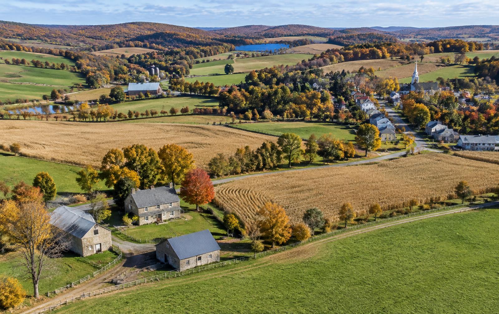 Farm fields, stone farmhouses, and a village of rooftops in rolling countryside